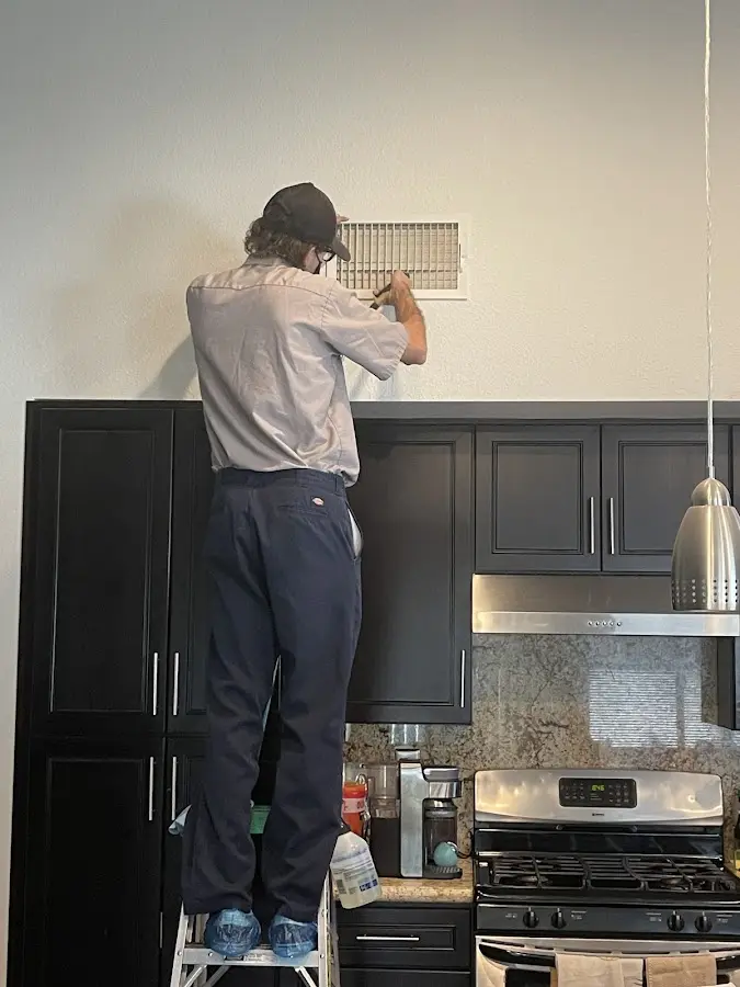 Technician inspecting an air vent during HVAC service in Columbine